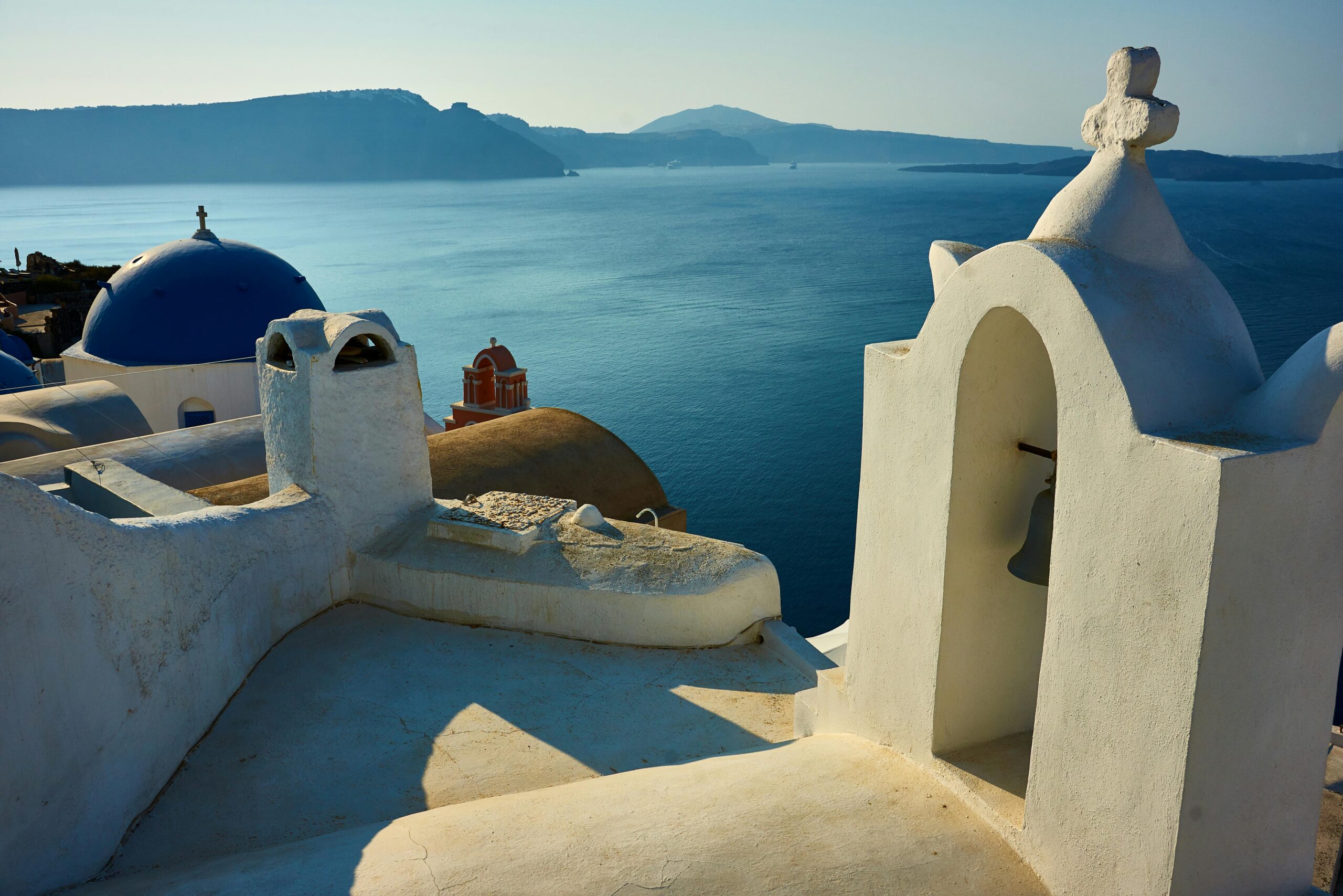 A picturesque view of Santorini's whitewashed architecture with a blue dome and ocean backdrop.