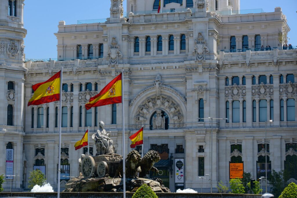 Cybele Palace in Madrid adorned with flying Spanish flags and a stunning fountain.